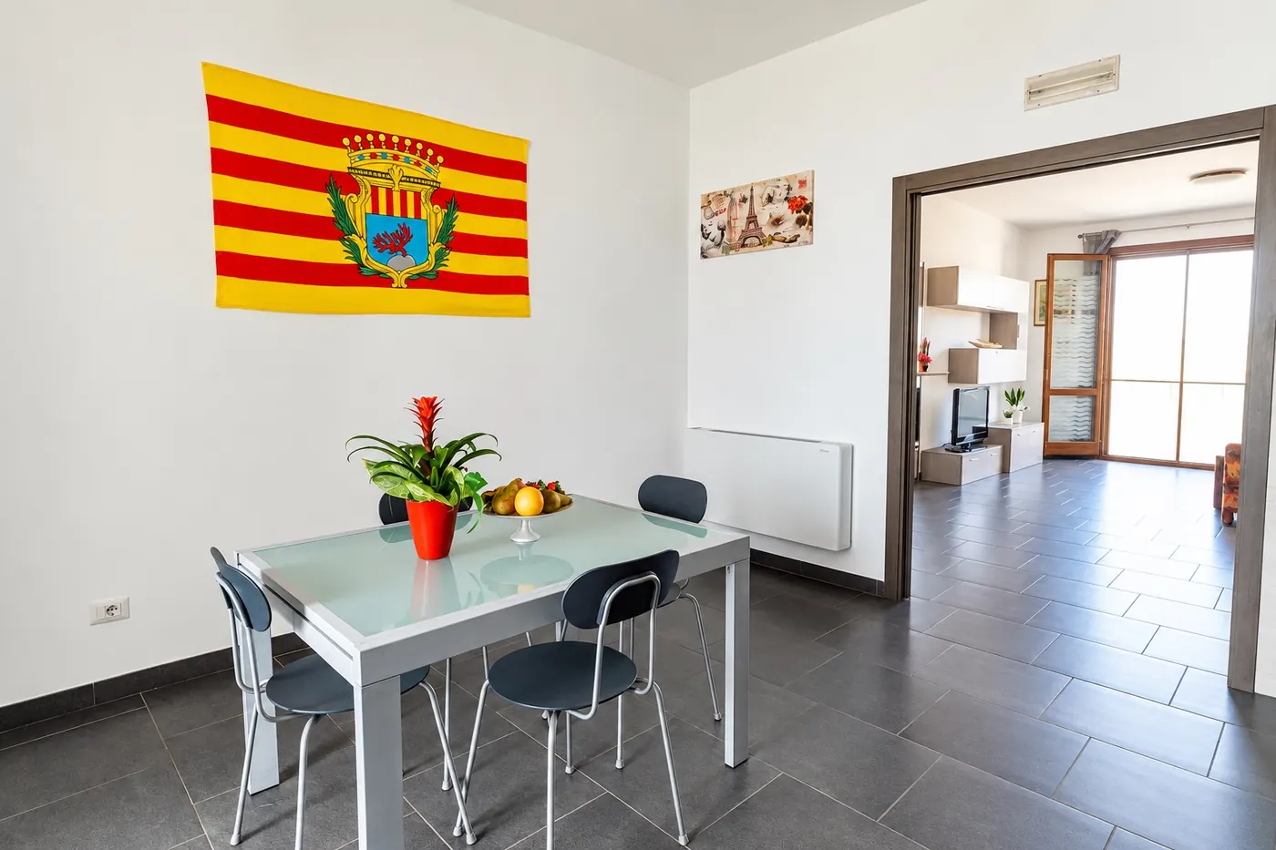 La zona pranzo con la bandiera di Alghero e il soggiorno sullo sfondo